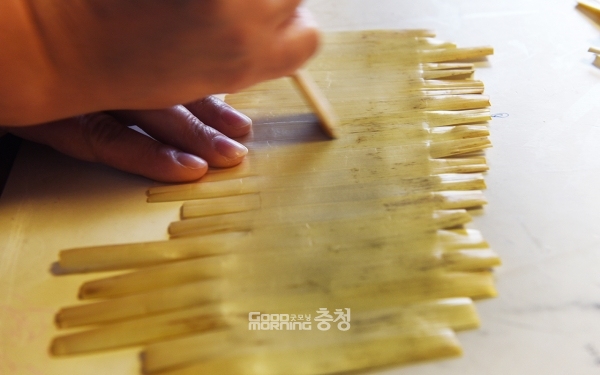 양면지에 붙인 보릿대를 꼼꼼하게 눌러주고 있다.