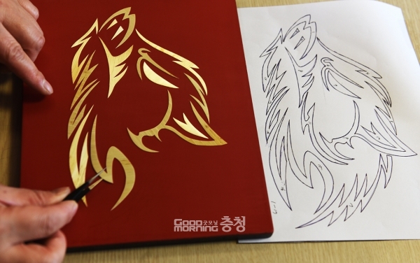 도안에 맞춰 다듬어진 보릿대 조각을 붙이고 있다.