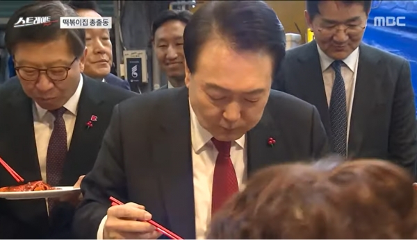 작년 12월 부산엑스포 유치 실패 후 부랴부랴 재벌 총수를 대동해 부산 국제시장에서 '떡볶이 먹방 쇼'를 벌였던 윤석열 대통령의 모습.(출처 : MBC 스트레이트 영상 갈무리/굿모닝충청 조하준 기자)