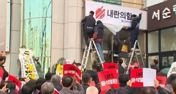 11일 국민의힘 울산시당을 찾아 간판에 '내란의힘'과 빨간 탱크 로고가 적힌 부착 현수막을 붙이며 항의하고 있는 시민들의 모습.(사진 제공=시민언론 민들레 김성진 기자)