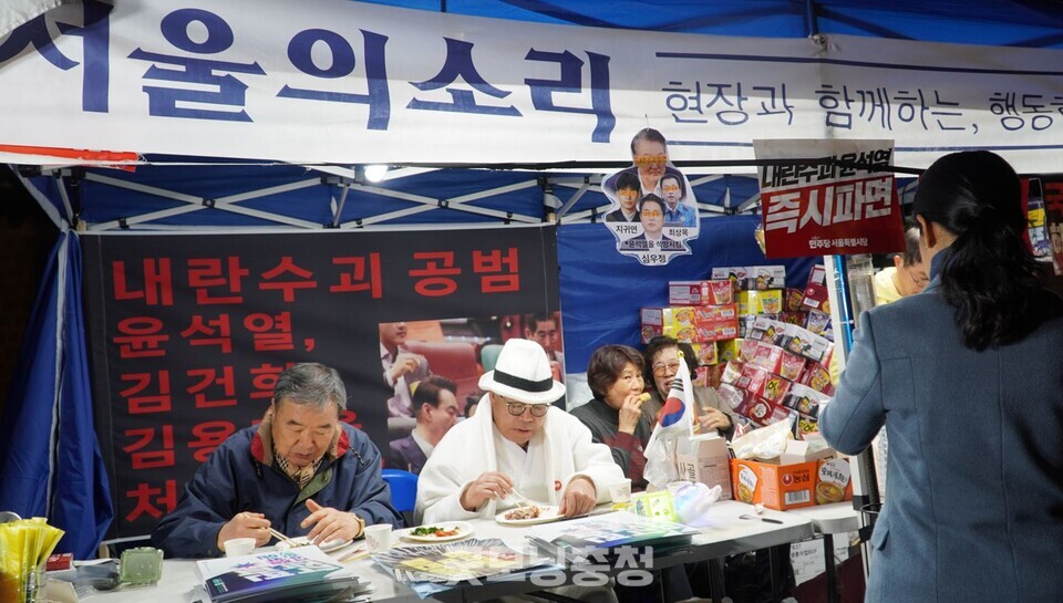 15일 오후 서울 광화문 앞에서 내란수괴 윤석열 파면 촉구 범시민대회가 개최됐다. 서울의소리 천막에서 백은종 대표(흰 모샂)가 간식을 먹고 있다. (사진=굿모닝충청 설인호 기자)