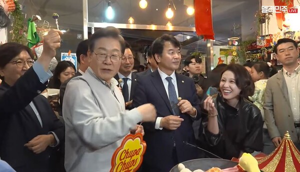 더불어민주당 이재명 대선 후보가 7일 예산 전통시장 사탕가게에서 구입한 막대사탕을 일행들과 함께 나눠먹고 있다.  (사진=델리민주 캡처)