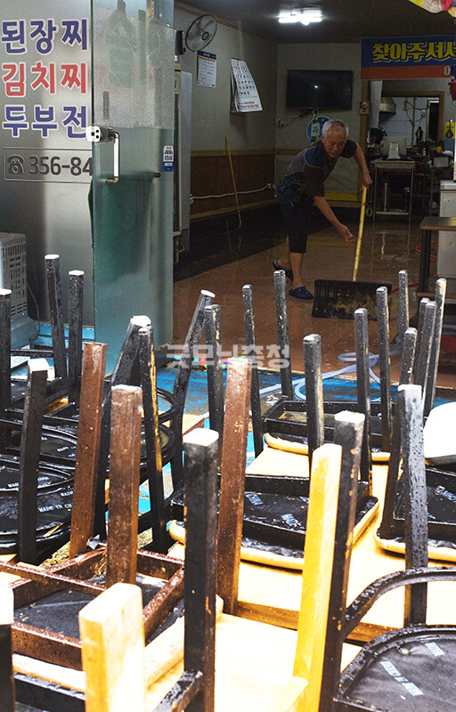 당진 전통시장의 한 식당에서 한 주민이 집기를 내놓은 뒤 물을 빼내고 있다​(사진=채원상 기자)